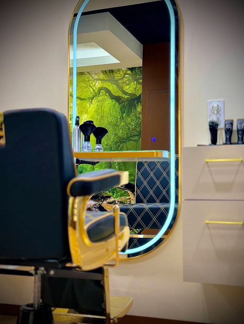 Intérieur premium du salon Viktorio : miroir doré, fauteuil de coiffure et décor nature